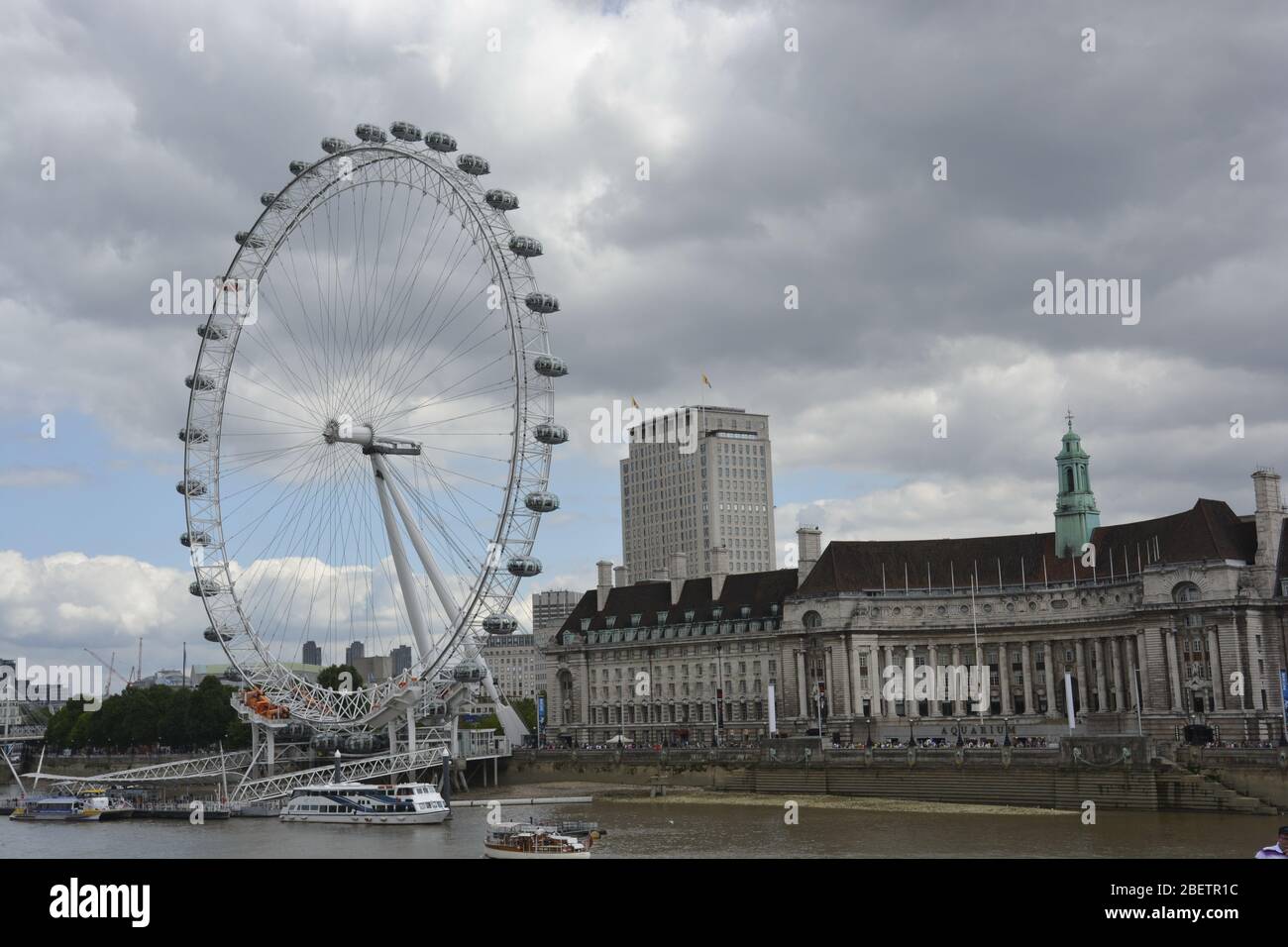 Il London Eye è situato su un'area di cornice lignea e nuvolosa, con il London Dungeon nel telaio centrale e il London Aquarium sul telaio destro. Soprattutto cielo nuvoloso e un po ' Foto Stock