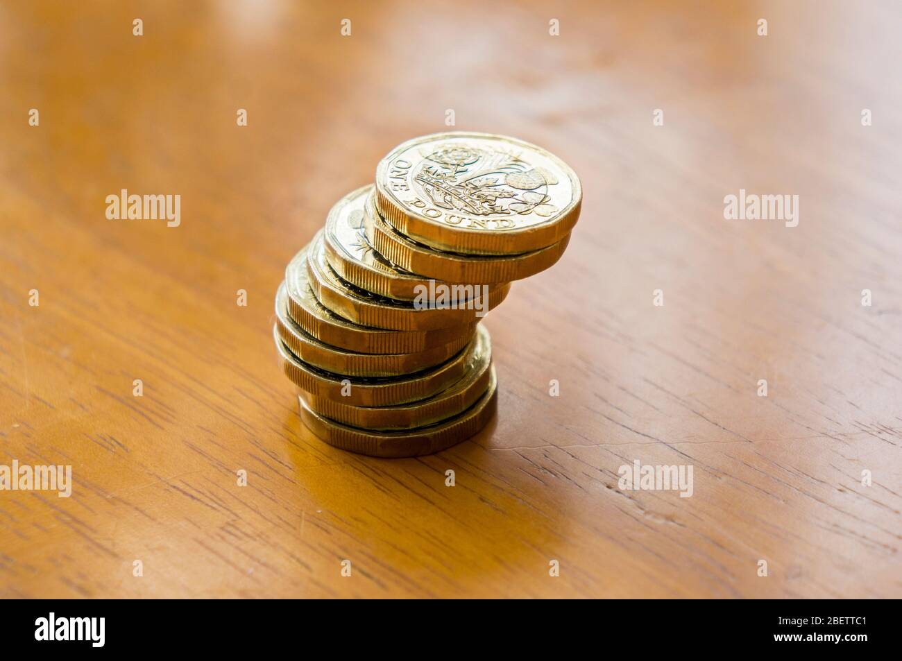 Nuove monete da una sterlina in una pila su un tavolo Foto Stock
