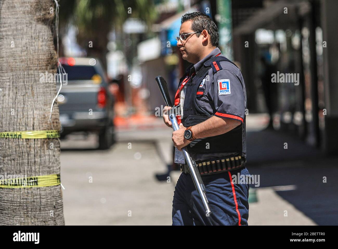 Guardia della società di sicurezza privata, SEPSA cammina con la sua arma da fuoco dopo aver raccolto denaro dai locali commerciali del Centro di Hermosillo Foto Stock