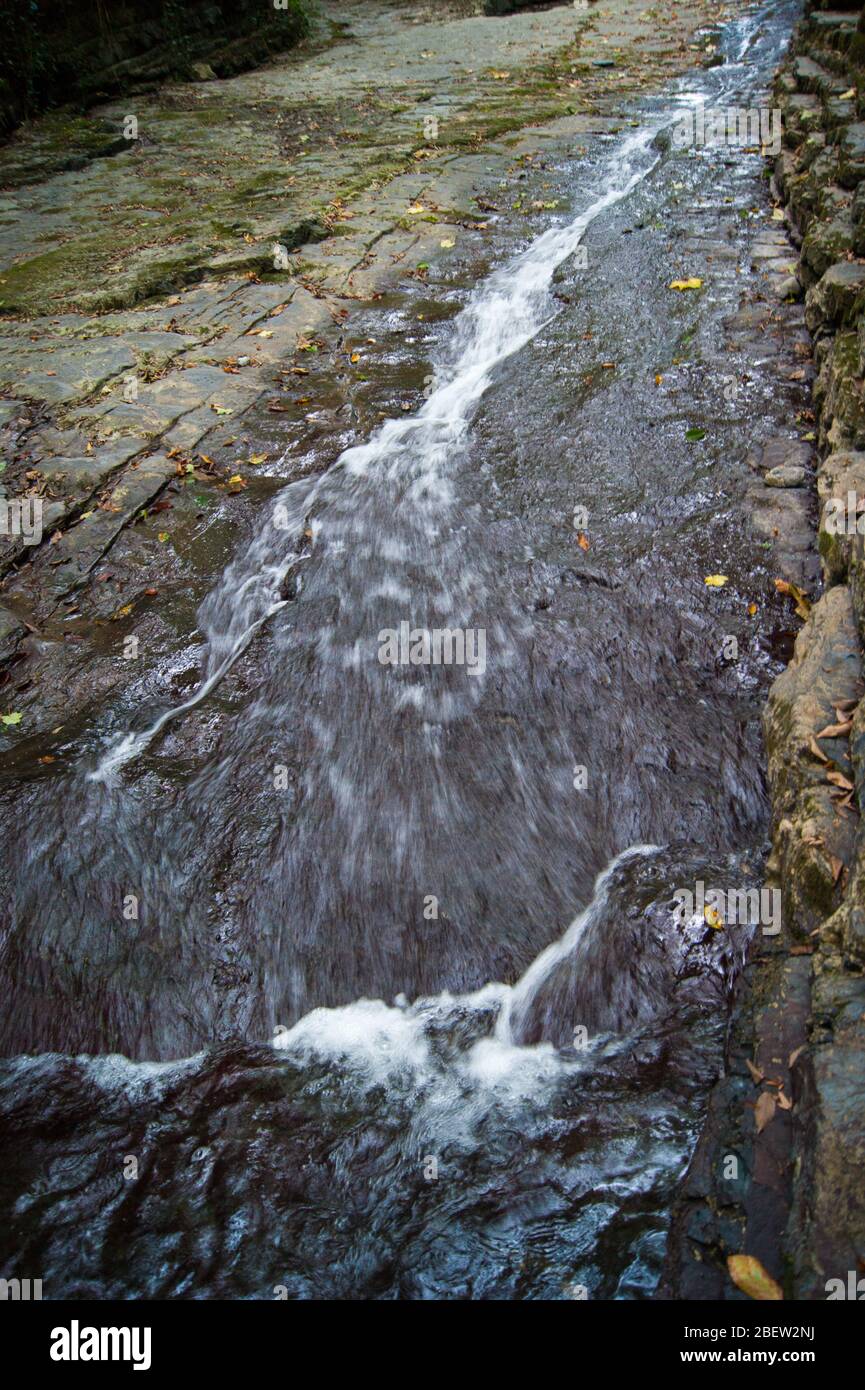 Una piccola cascata di montagna con acqua ghiacciata molto pulita. Gola. Roccia, pietra, acqua, edera. Caucaso, estate, escursione, turismo, vacanze, vacanze, viaggi Foto Stock