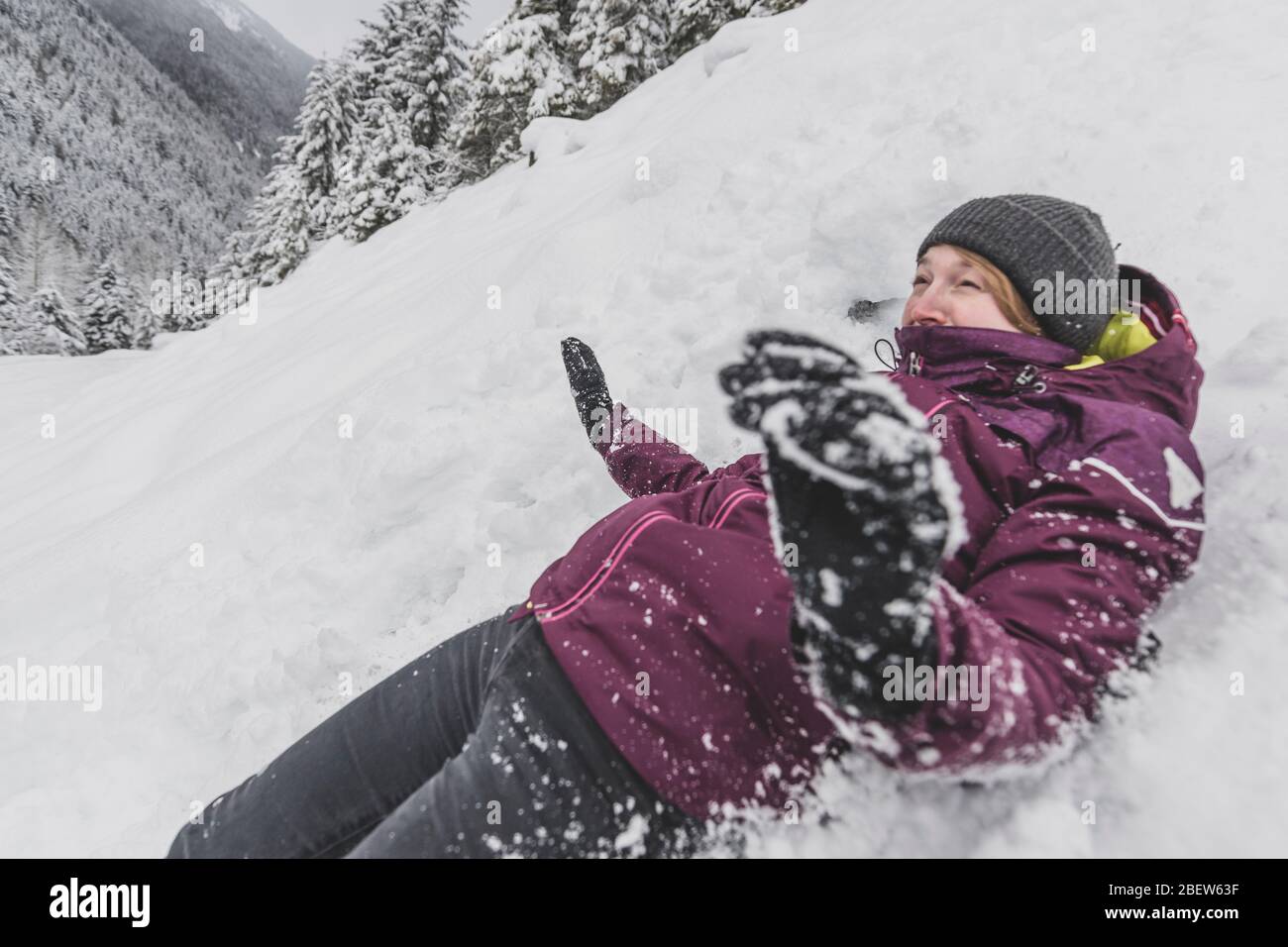 Giovane donna con cappello scorrevole veloce nella neve discesa divertente viso Foto Stock