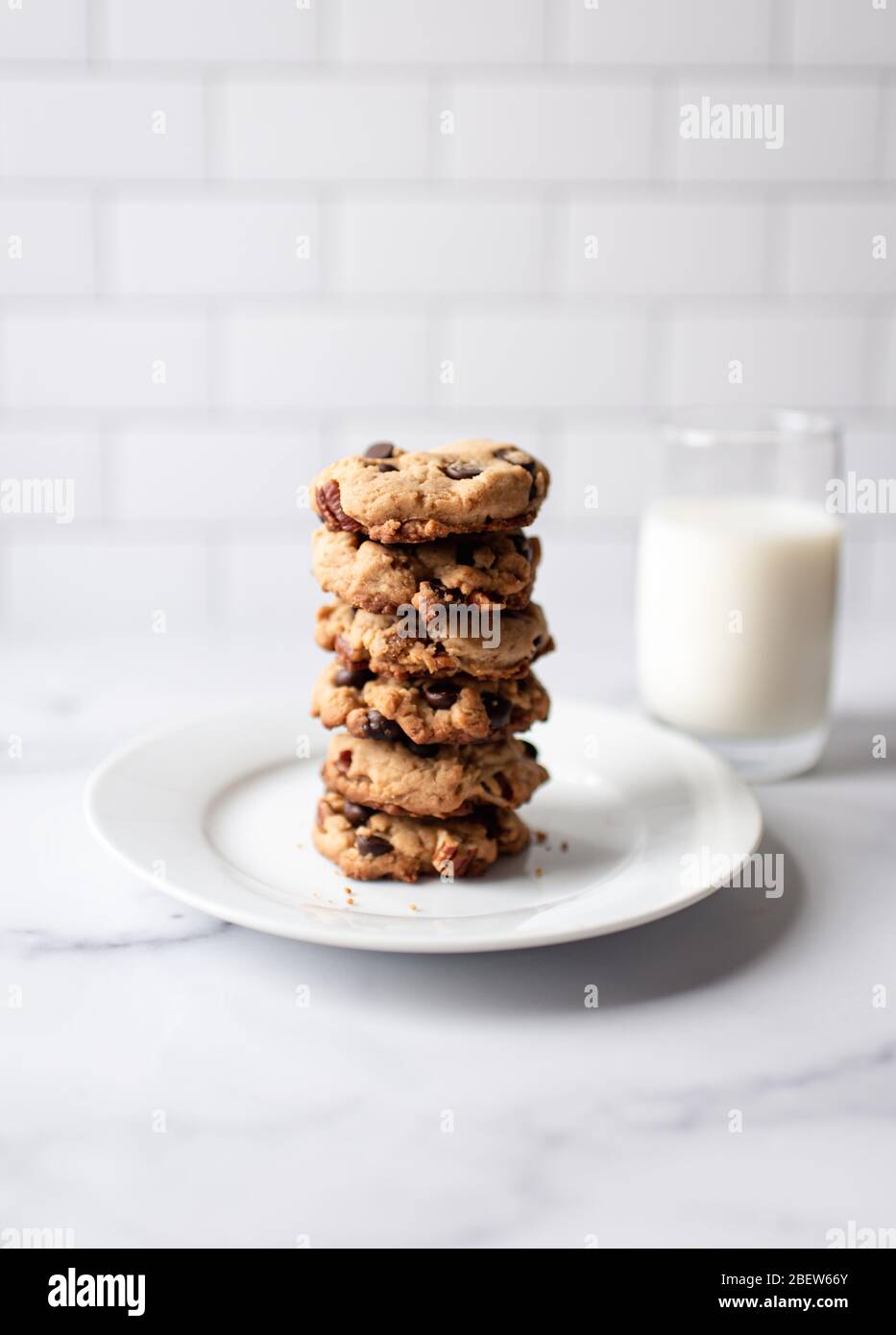 Pila di biscotti al cioccolato e latte su bancone in marmo bianco. Foto Stock