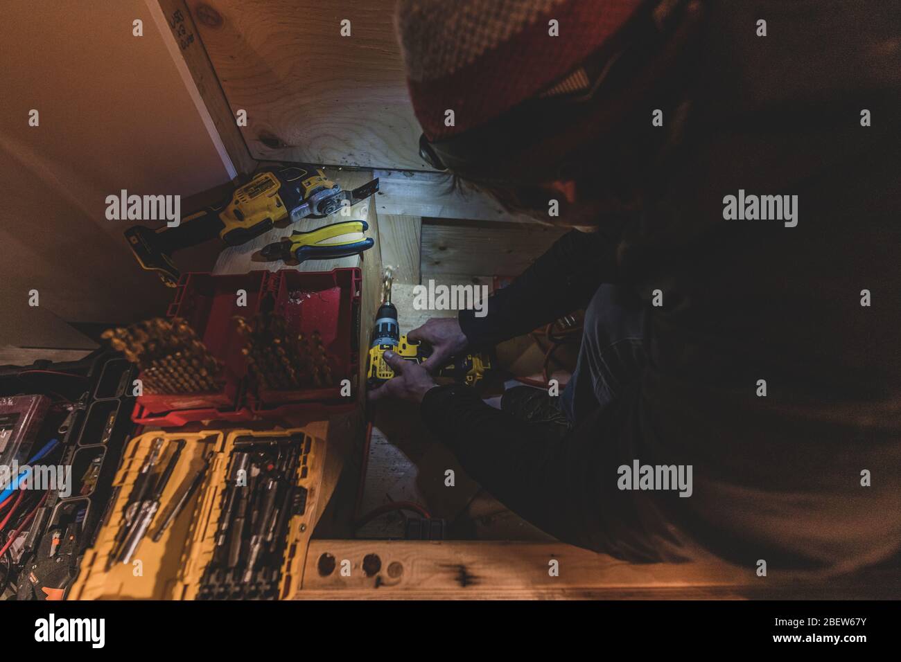Vista dall'alto di Man Drilling in legno in condizioni di scarsa illuminazione con lampada frontale Foto Stock