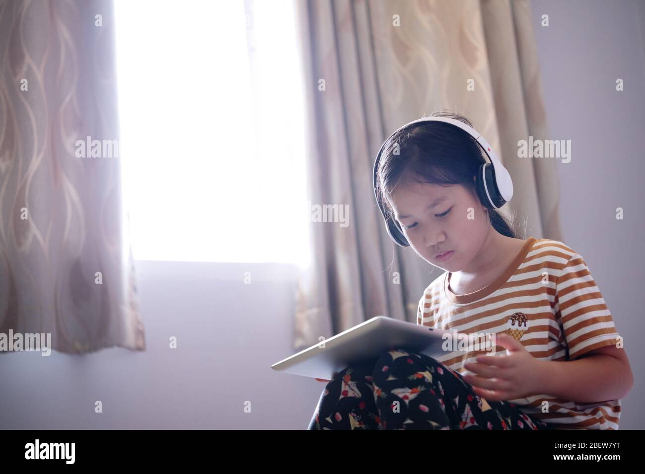 Le ragazze usano un tablet e ascoltano musica con le cuffie Foto Stock