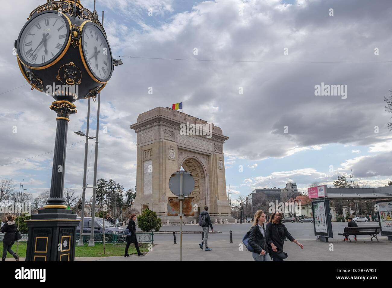 Moody vista dell'arco trionfale nazionale rumeno a bucarest, persone e trasporto del traffico Foto Stock