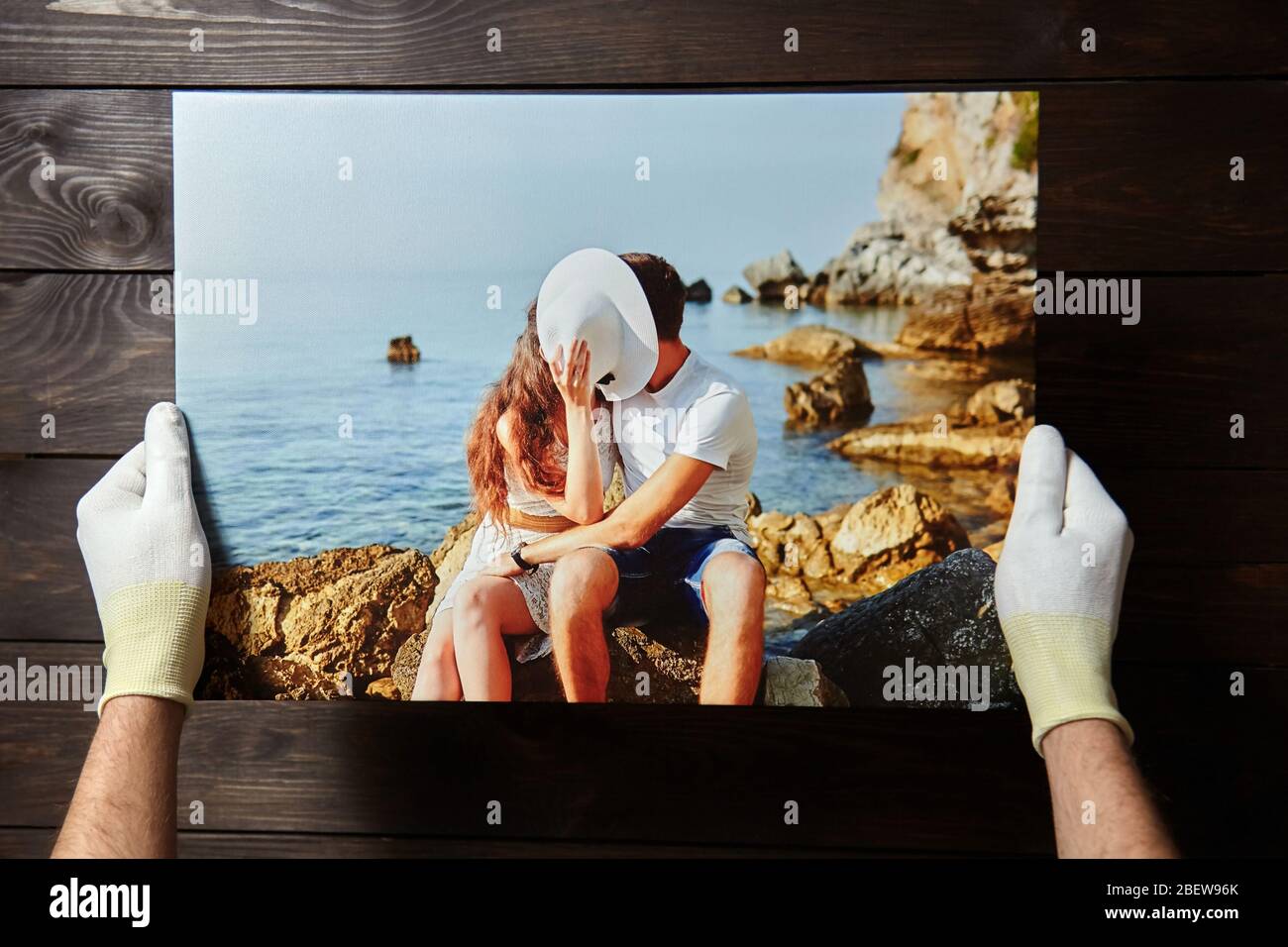 Fotografia stampata su tela con metodo di avvolgimento della galleria di tela stretching. Foto di baciare la coppia innamorata è in mano maschile Foto Stock