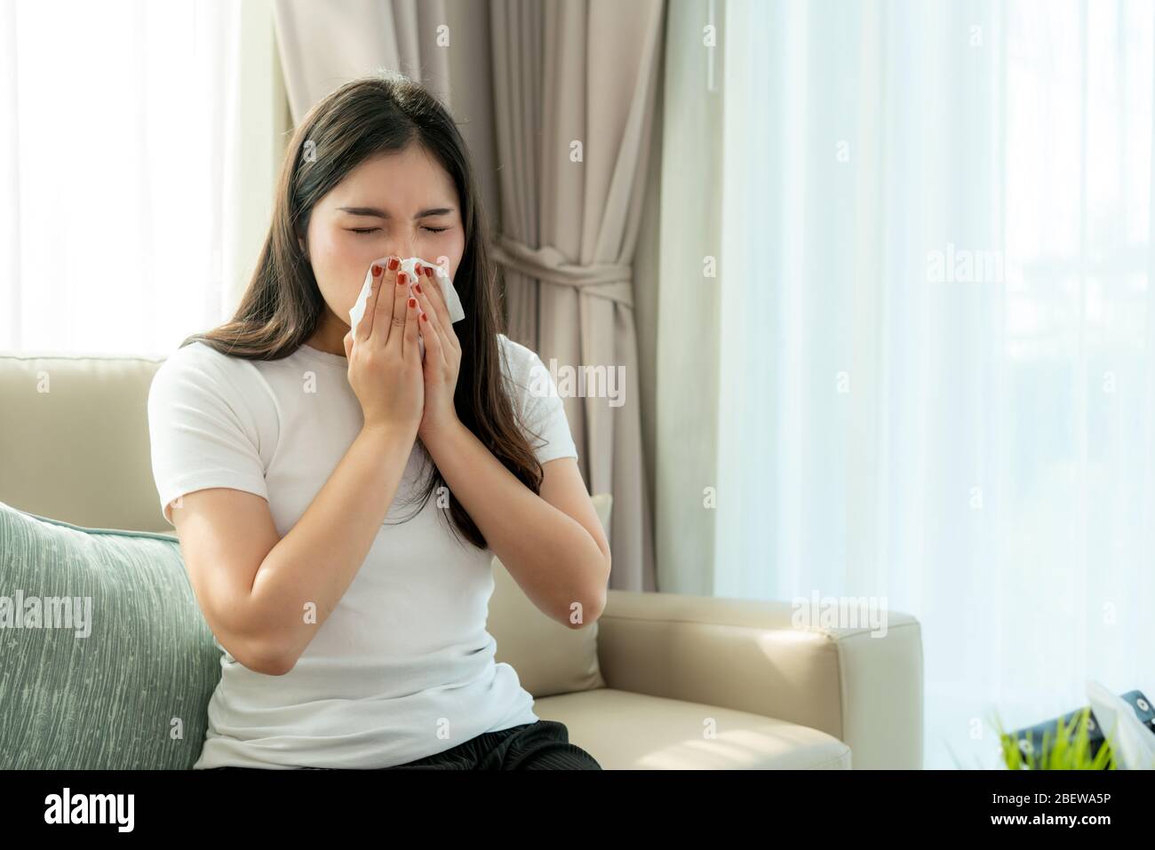 Donna asiatica malata e triste con starnuti sul naso e tosse fredda su carta tissutale perché influenza e batteri deboli o virus da polvere tempo o fumo Foto Stock