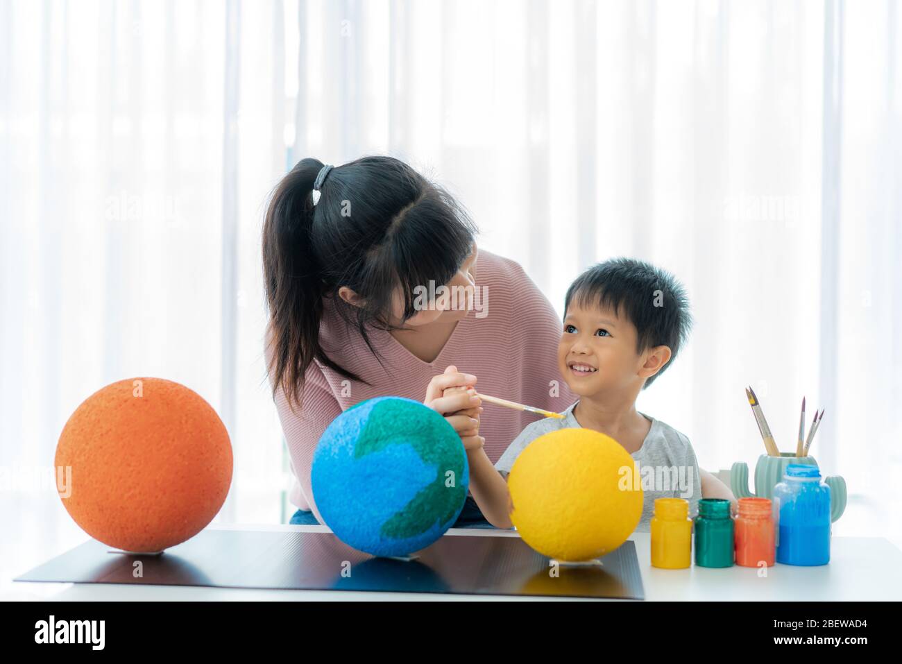 Bambino asiatico dello studente di preschool con madre che dipinge la luna imparando circa il sistema solare a casa, Homeschooling e apprendimento a distanza. Foto Stock