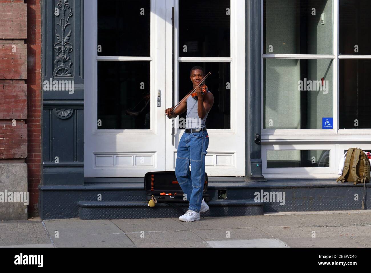 Una persona gioca un violino su una strada vuota nel quartiere SoHo di Manhattan durante il coronavirus COVID-19.... PER ULTERIORI INFORMAZIONI, VEDERE LA DIDASCALIA COMPLETA Foto Stock