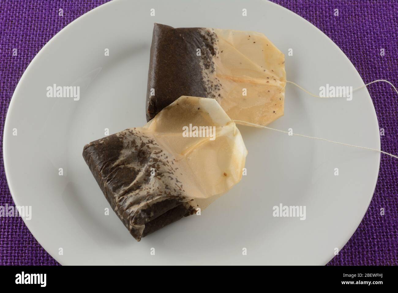 Due tovaglie nere usate su un piatto bianco su tovaglia viola dopo aver fatto il tè freddo Foto Stock