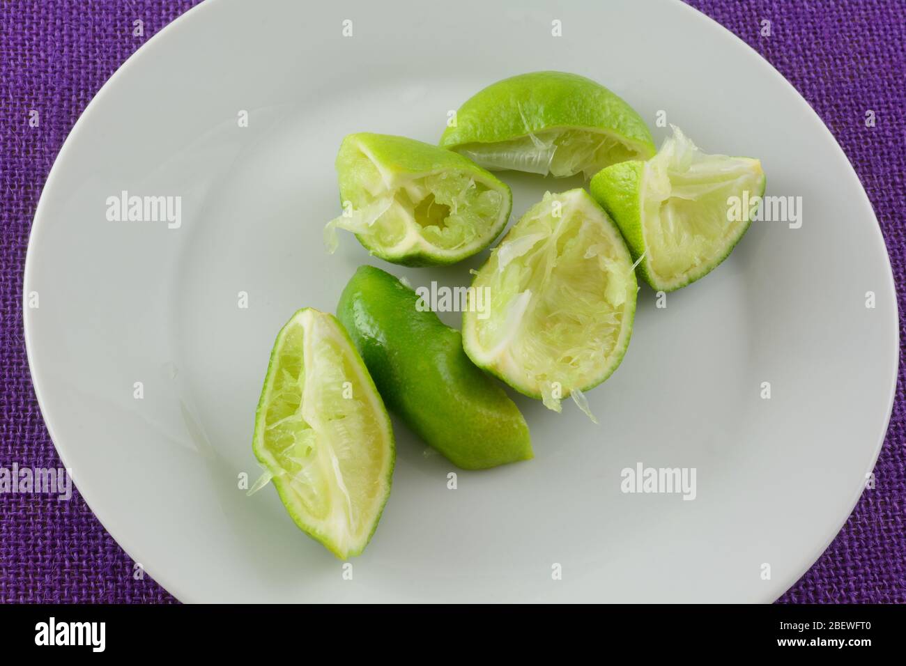 Spremute i cunei di lime dal fare il succo su piatto bianco Foto Stock