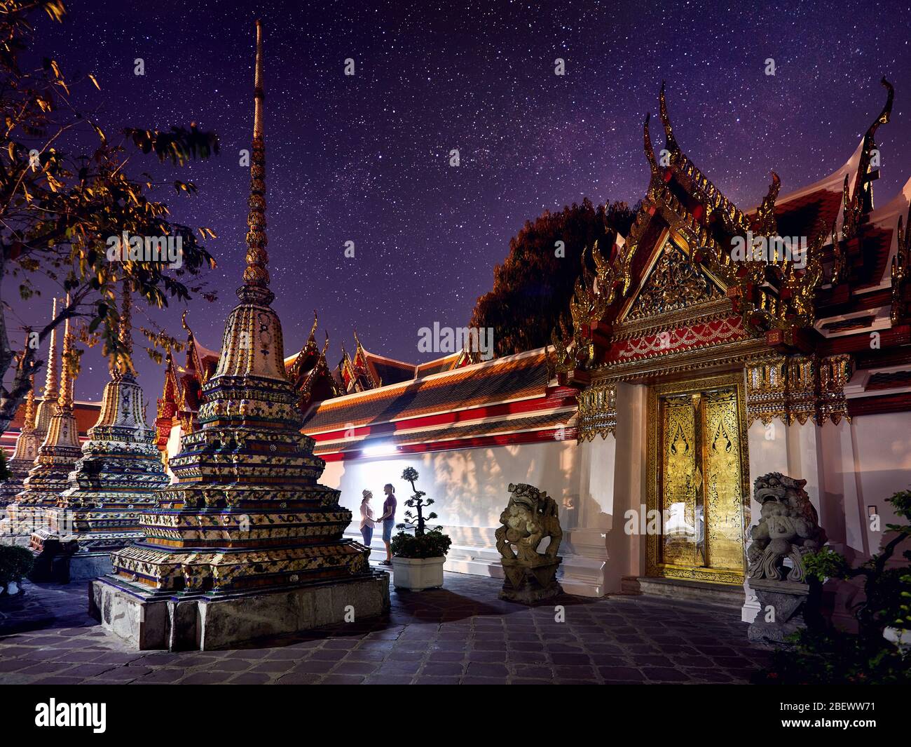 Coppia giovane nel tempio buddista complesso Wat Pho a Bangkok alla magica notte cielo stellato in background in Thailandia Foto Stock