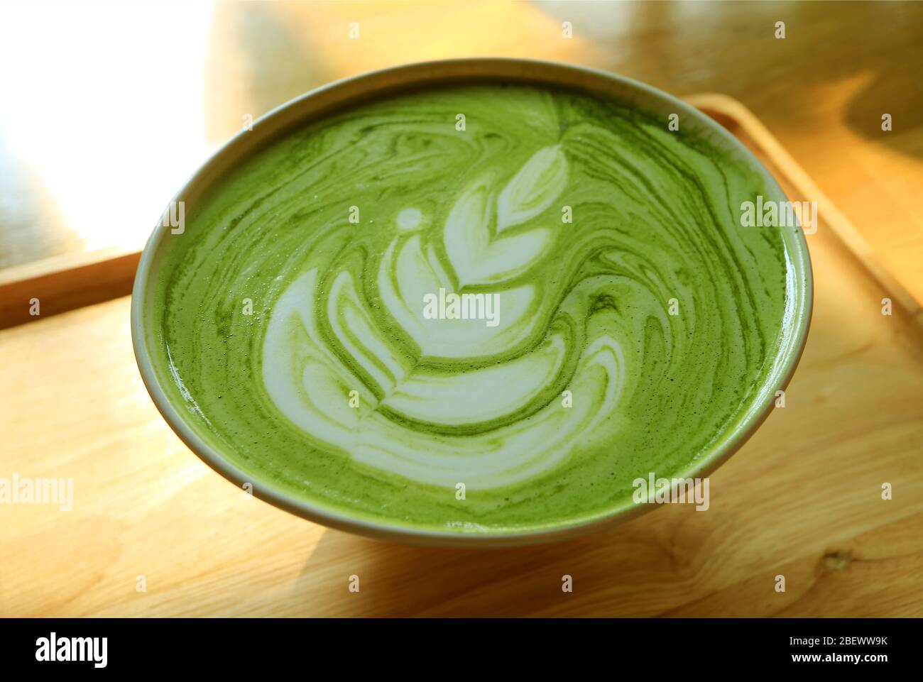 Closeup una tazza di latte caldo di tè verde Matcha su un vassoio di legno Foto Stock