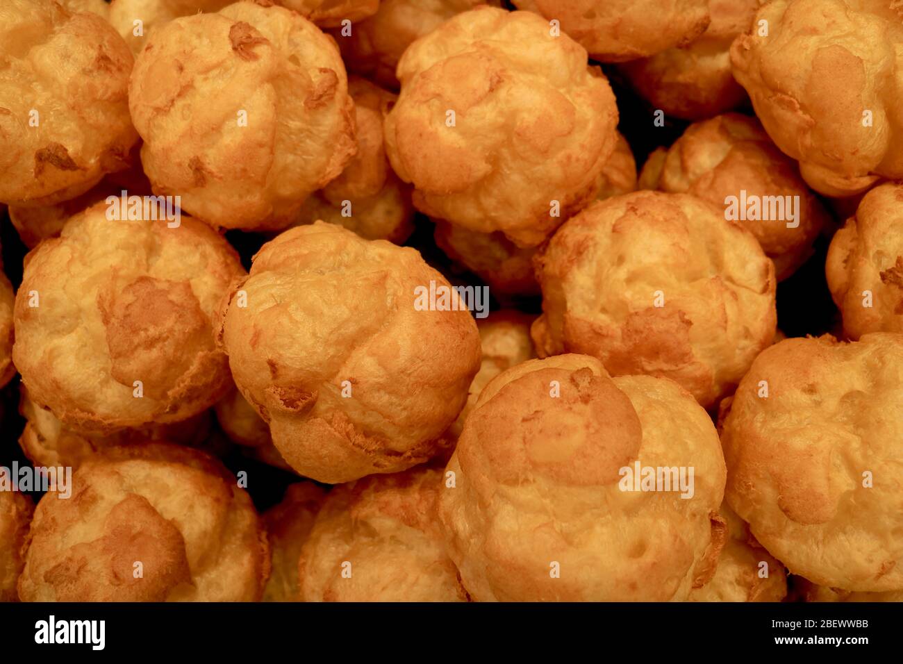 Pile di palle di pasticceria francese Choux appena sfornate durante il raffreddamento prima che la crema riempia Foto Stock