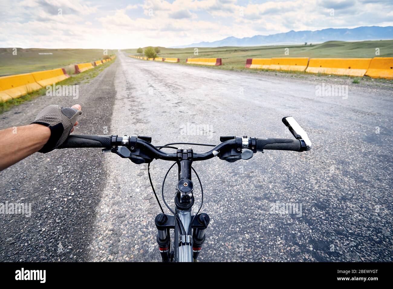 Cavaliere guanti in azienda manubri di mountain bike sulla autostrada strada nel deserto. Foto Stock