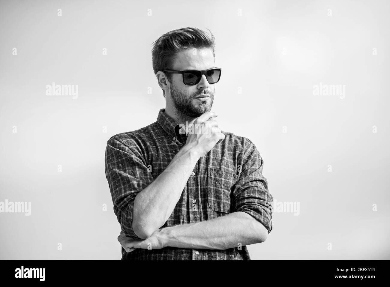 Protezione ultravioletta concetto. Visione perfetta. Vedere chiaro. Bel ragazzo di indossare occhiali da sole. Hipster uomo nel quartiere alla moda di occhiali da sole. Occhiali da sole alla moda. Uomo modello di occhiali all'aperto il cielo blu sullo sfondo. Foto Stock