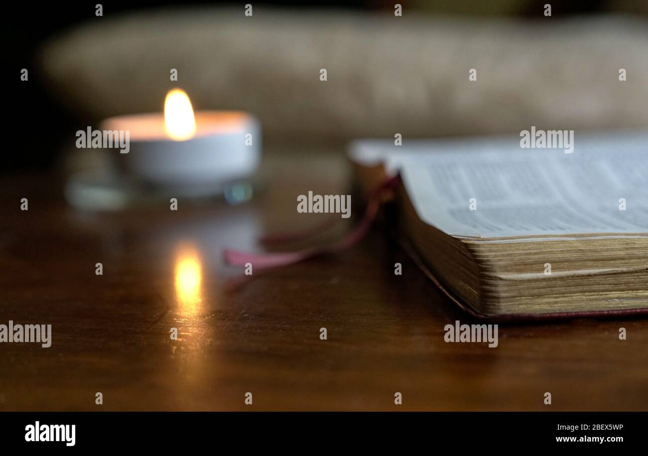 Apri la bibbia con la candela bruciante sul tavolo. Ambiente accogliente. Foto Stock