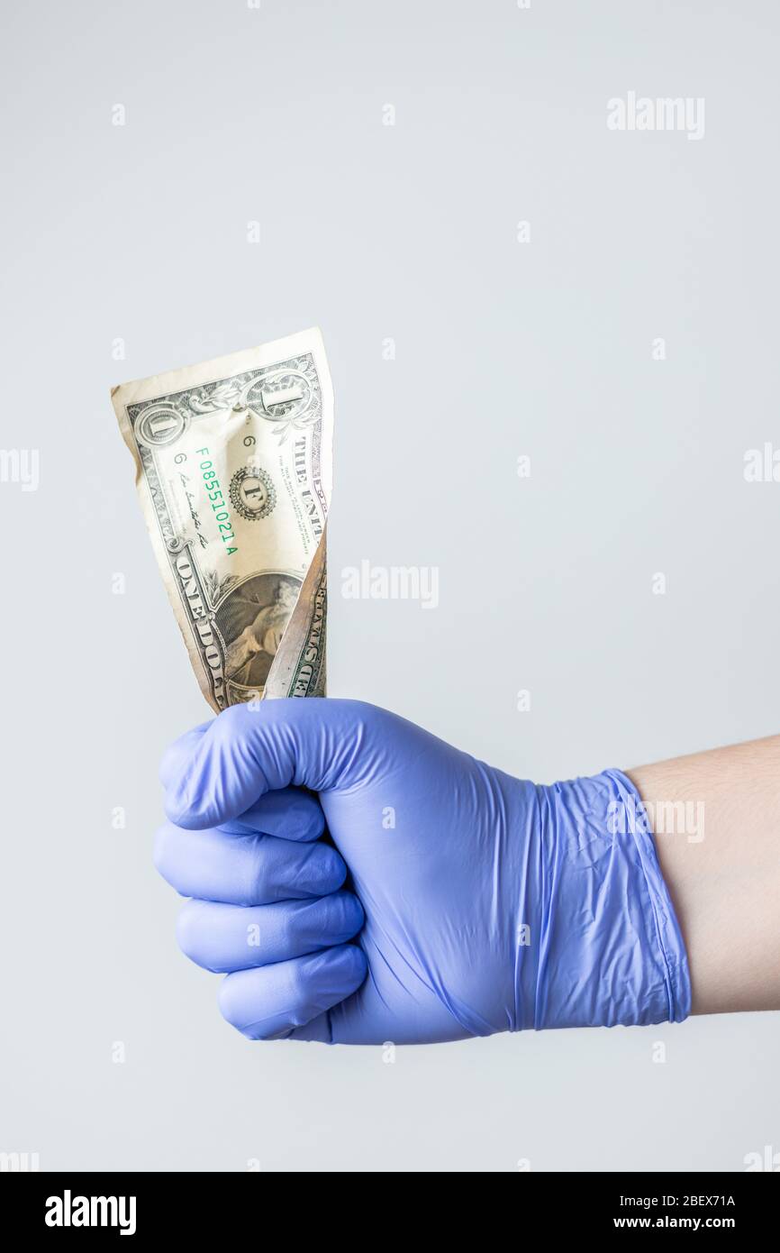mano con guanti in lattice blu con bolletta del dollaro. Concetto di crisi finanziaria coronavirus, covid-19 Foto Stock