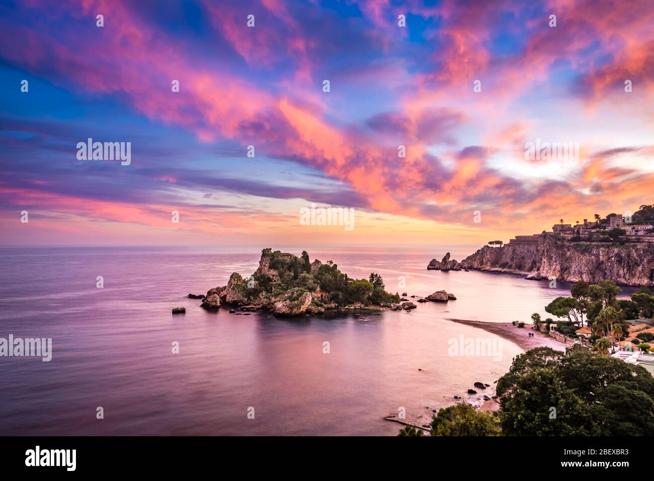 Vista incredibile del tramonto colorato sulla splendida baia della Riserva Naturale Isola Bella - un piccolo paradiso un'isola sulla costa di Taormina, Sicilia Foto Stock