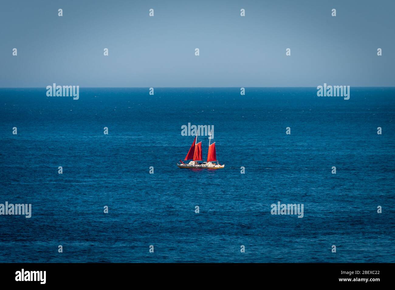 Yacht a vela rossa che galleggia nel Mar Mediterraneo, vicino alla costa azzurra di Taormina, Sicilia Foto Stock