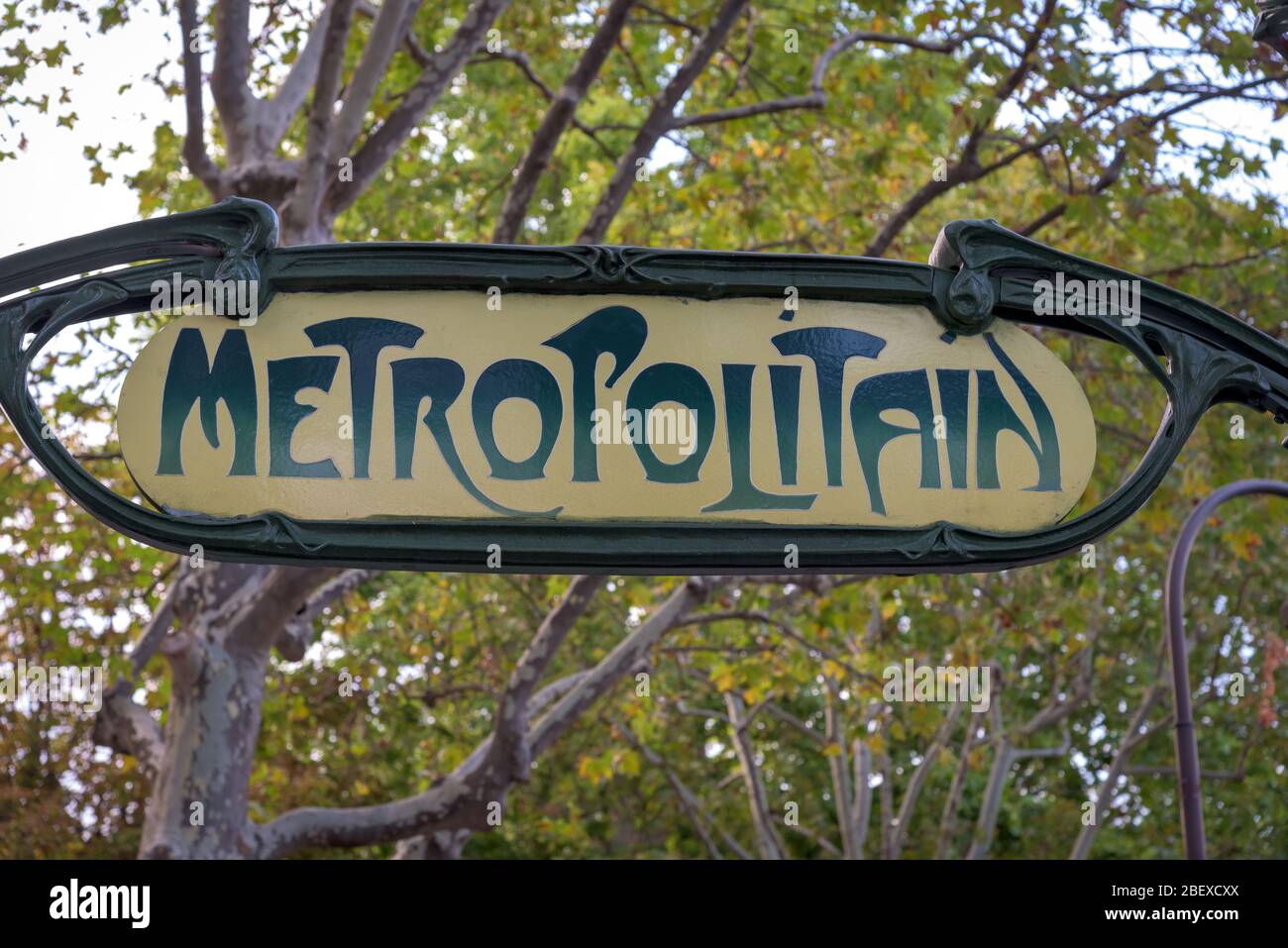 Segno giallo retrò Metropolitain della rete metropolitana di Parigi su uno sfondo verde alberato. Foto Stock