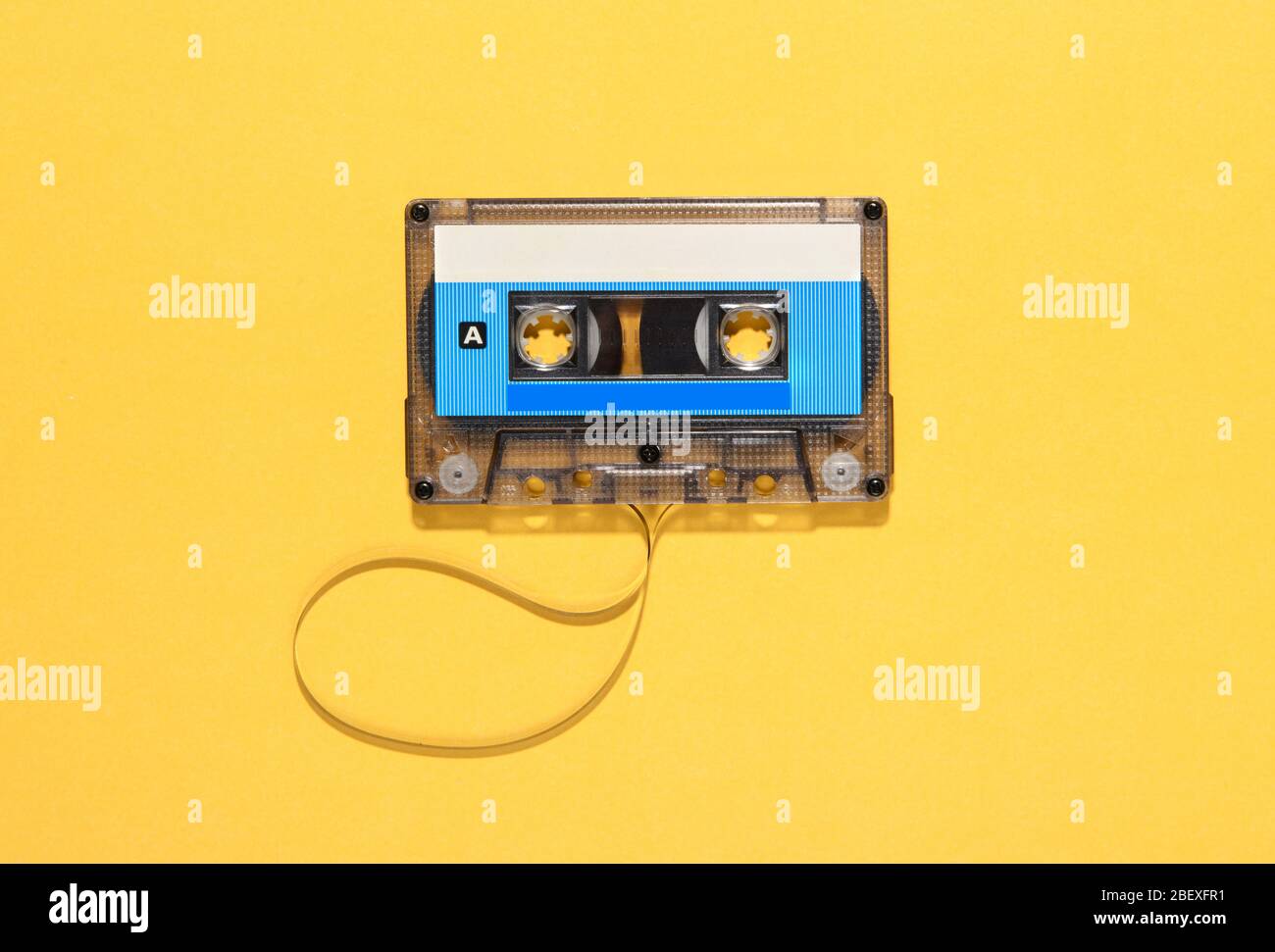 Cassetta audio vintage con bobina di nastro srotolata su giallo con spazio di copia visto come una forma piatta fermo vita Foto Stock
