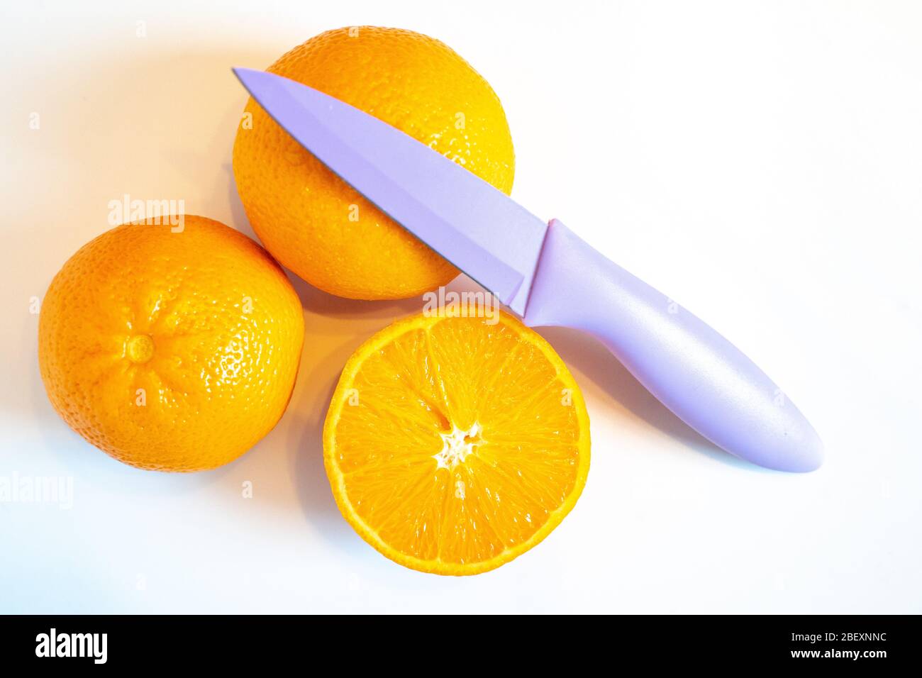 Tre metà di arancio con un coltello affilato su uno sfondo bianco Foto Stock