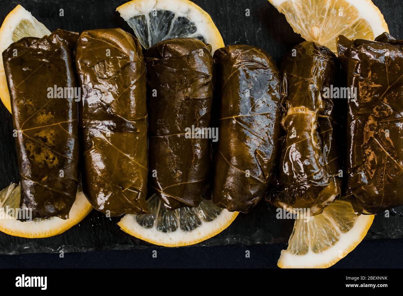 Dolma (foglie d'uva ripiene) vista dall'alto su sfondo nero. Cucina mediterranea piatti vegani Foto Stock