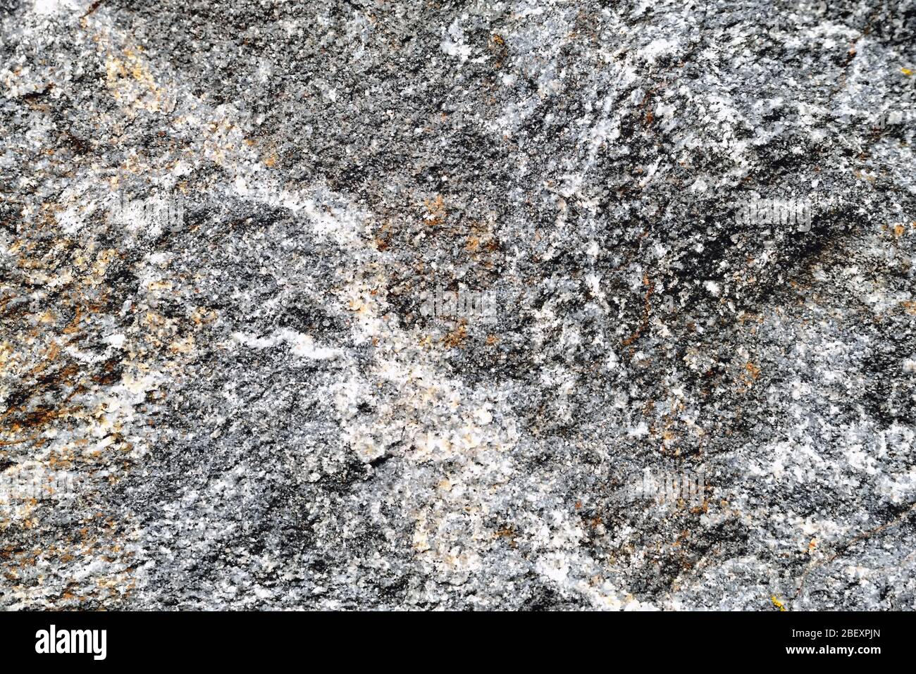 Fondo grigio in granito con strisce bianche e macchie ocra di struttura eterogenea Foto Stock