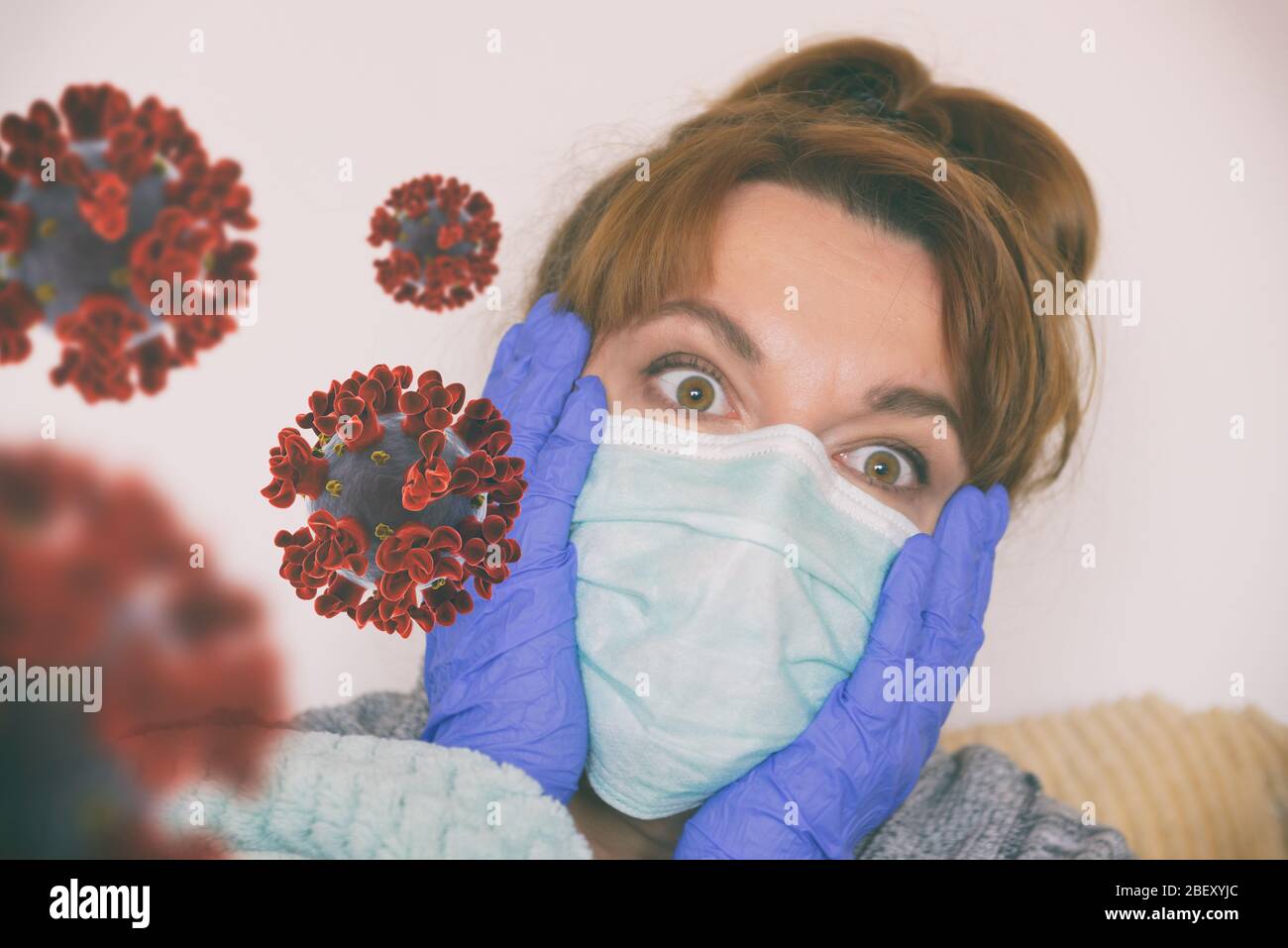 Donna spaventata seduta a casa con maschera e guanti protettivi. Concetto di paura pandemica del coronavirus Foto Stock