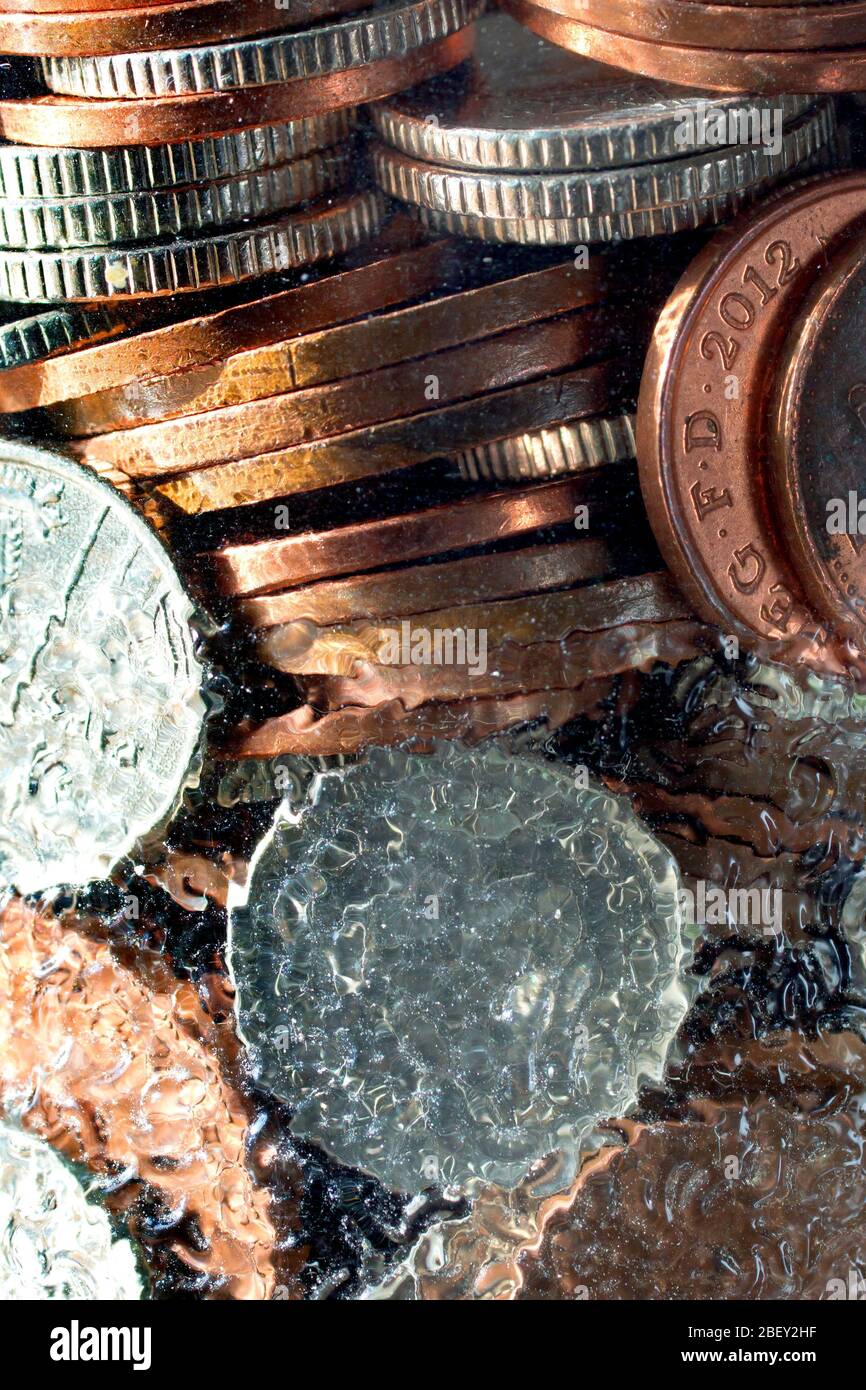 Primo piano di monete di bassa denominazione salvate in un vaso di vetro con fondo puntinato. Foto Stock