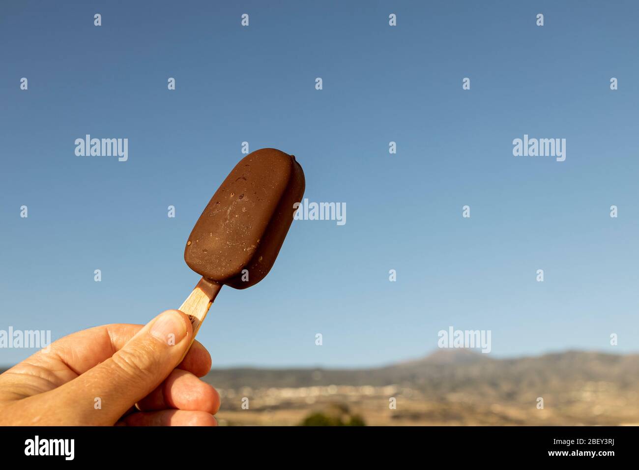 Gelato al cioccolato su bastone contro il cielo blu, Playa San Juan, Tenerife, Isole Canarie, Spagna Foto Stock