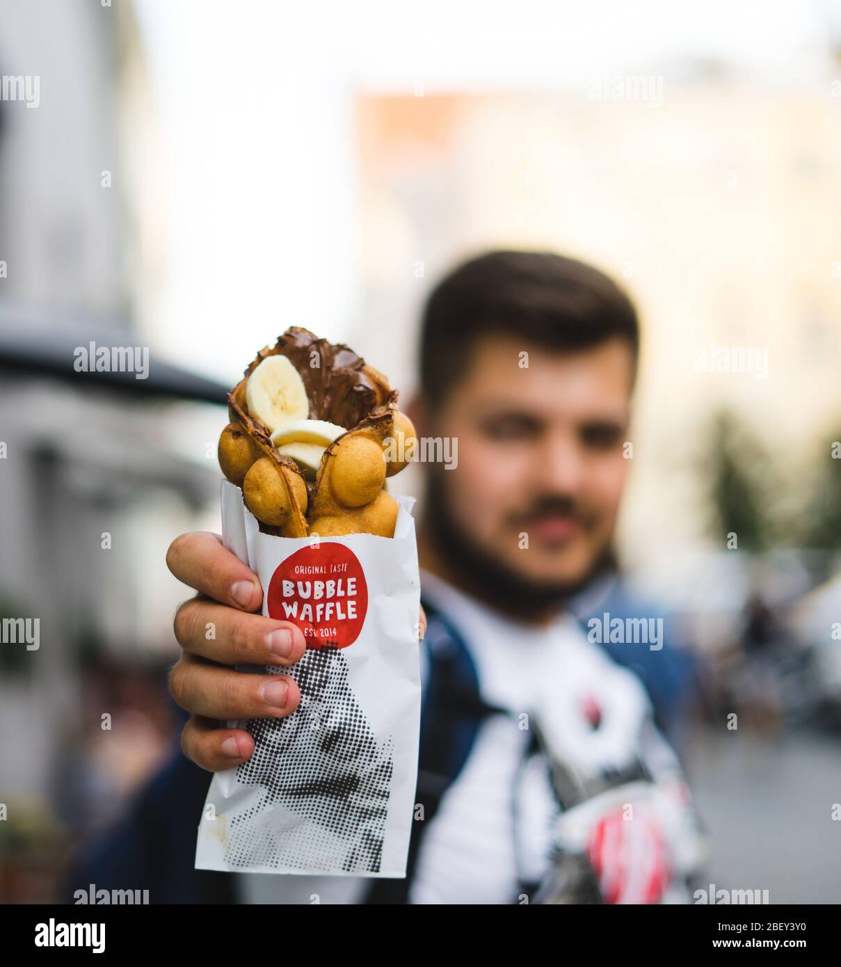 Giovane che tiene waffle con gelato, banane e cioccolato Foto Stock