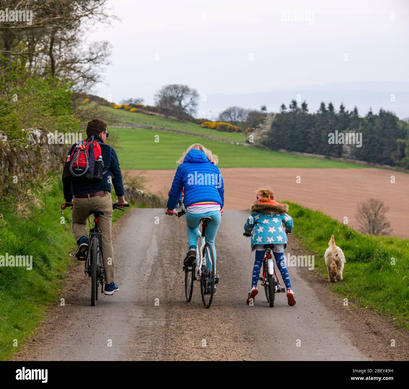 Famiglia in bicicletta sulla corsia di campagna durante Covid-19 Pandemic Coronavirus per l'esercizio quotidiano, East Lothian, Scozia, Regno Unito Foto Stock