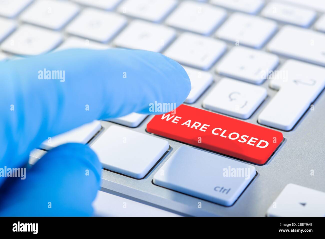Siamo concetto chiuso. Mano con guanto di protezione e tastiera con tasto rosso. Concetto di focolaio di coronavirus COVID-19 Foto Stock