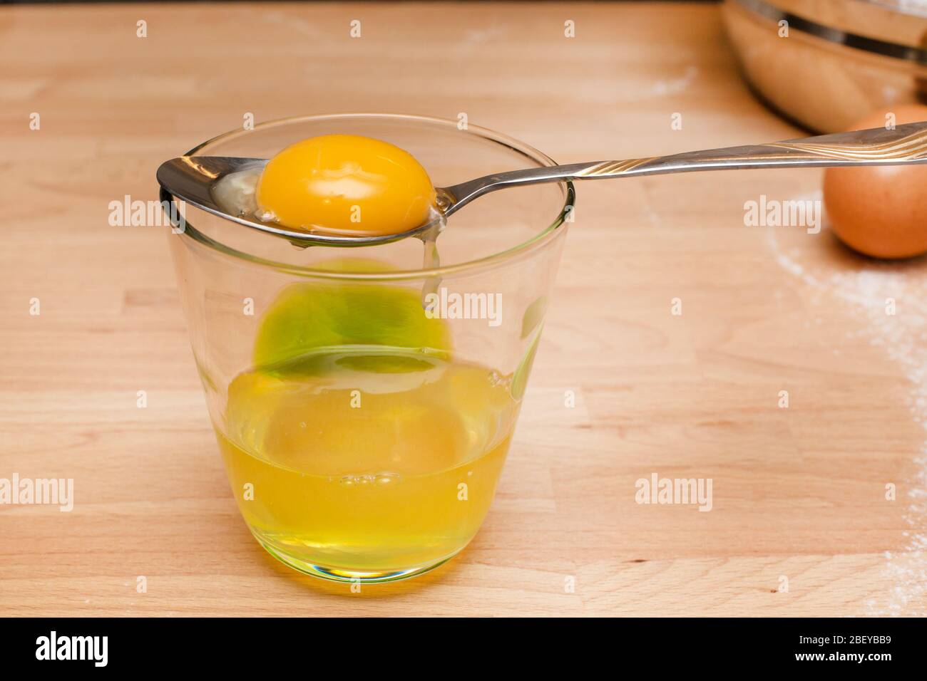 Close up materie tuorlo giallo separazione in cucchiaio e vetro con bianco d'uovo Foto Stock