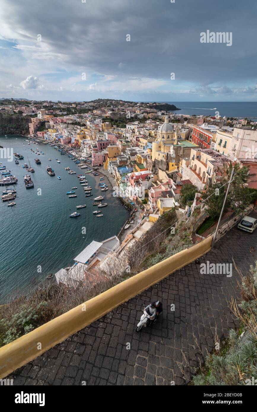 Vista della splendida Procida in estate soleggiata. Case colorate, caffè e ristoranti, barche da pesca e yacht a Marina Corricella, Foto Stock