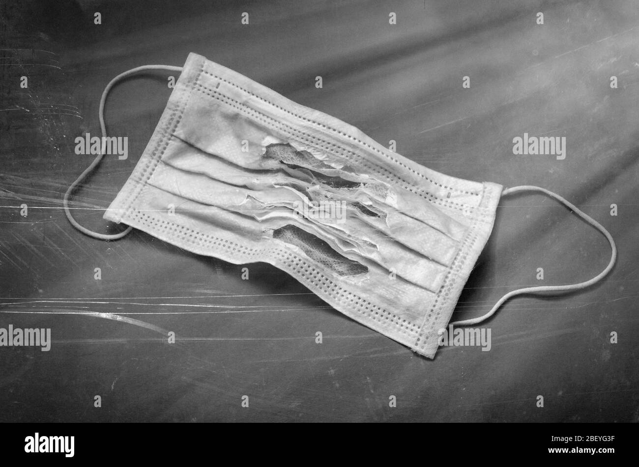 Maschera chirurgica non adatta. Primo piano della maschera medica strappata. Protezione individuale delle vie respiratorie con danni significativi. Messa a fuoco selettiva. Phot vintage styling Foto Stock
