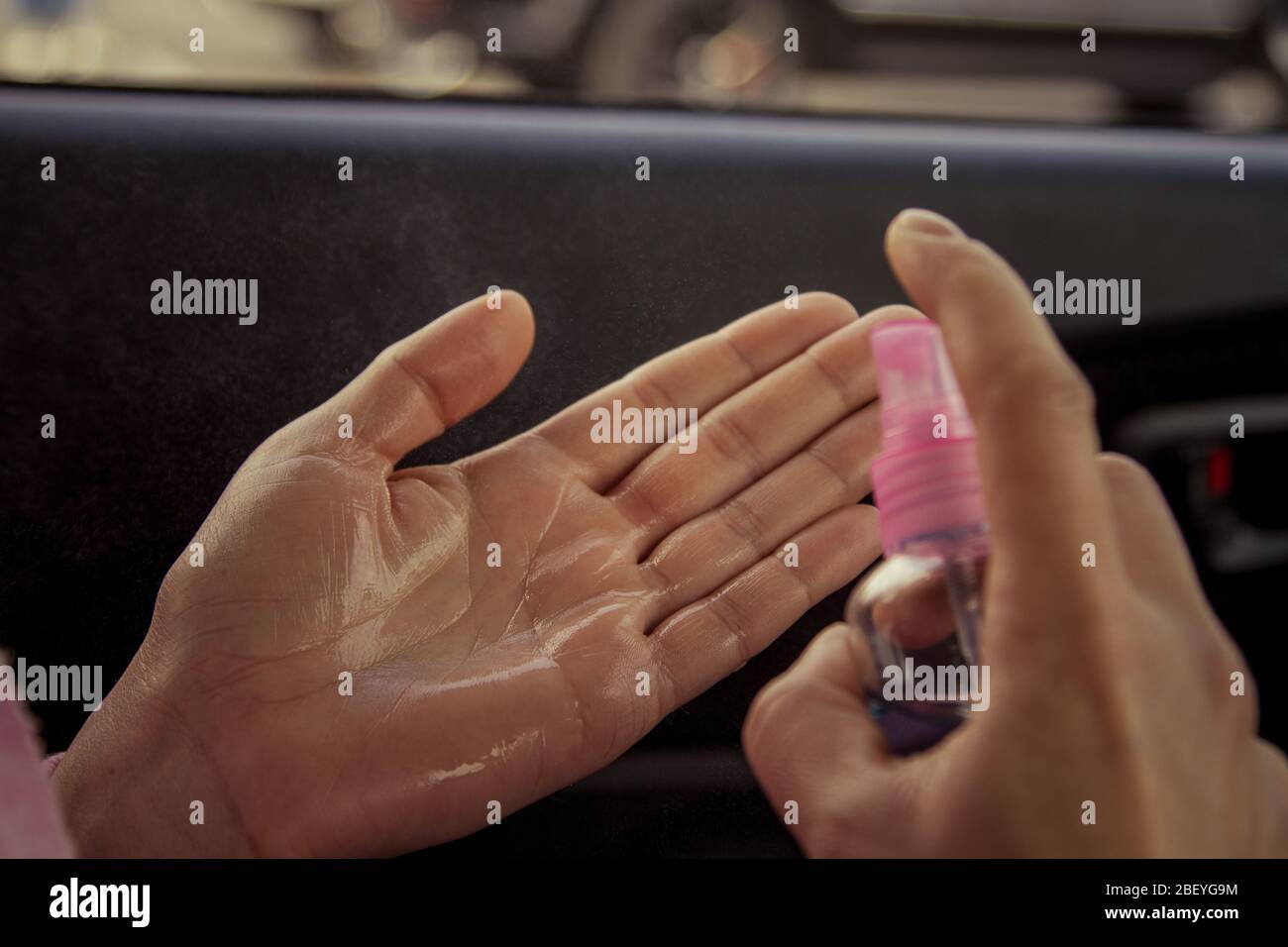 Disinfezione delle mani con un disinfettante a base di alcool in auto. Disinfezione delle mani dopo l'uso della vettura durante un'epidemia. Foto Stock
