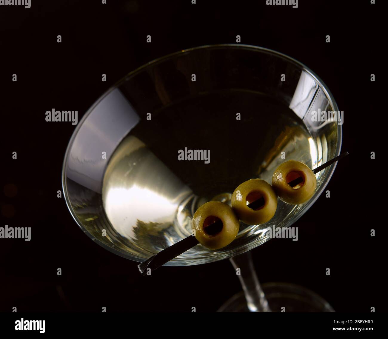 Martini cocktail con olive verdi su sfondo nero. Copia spazio su uno sfondo nero. Foto Stock