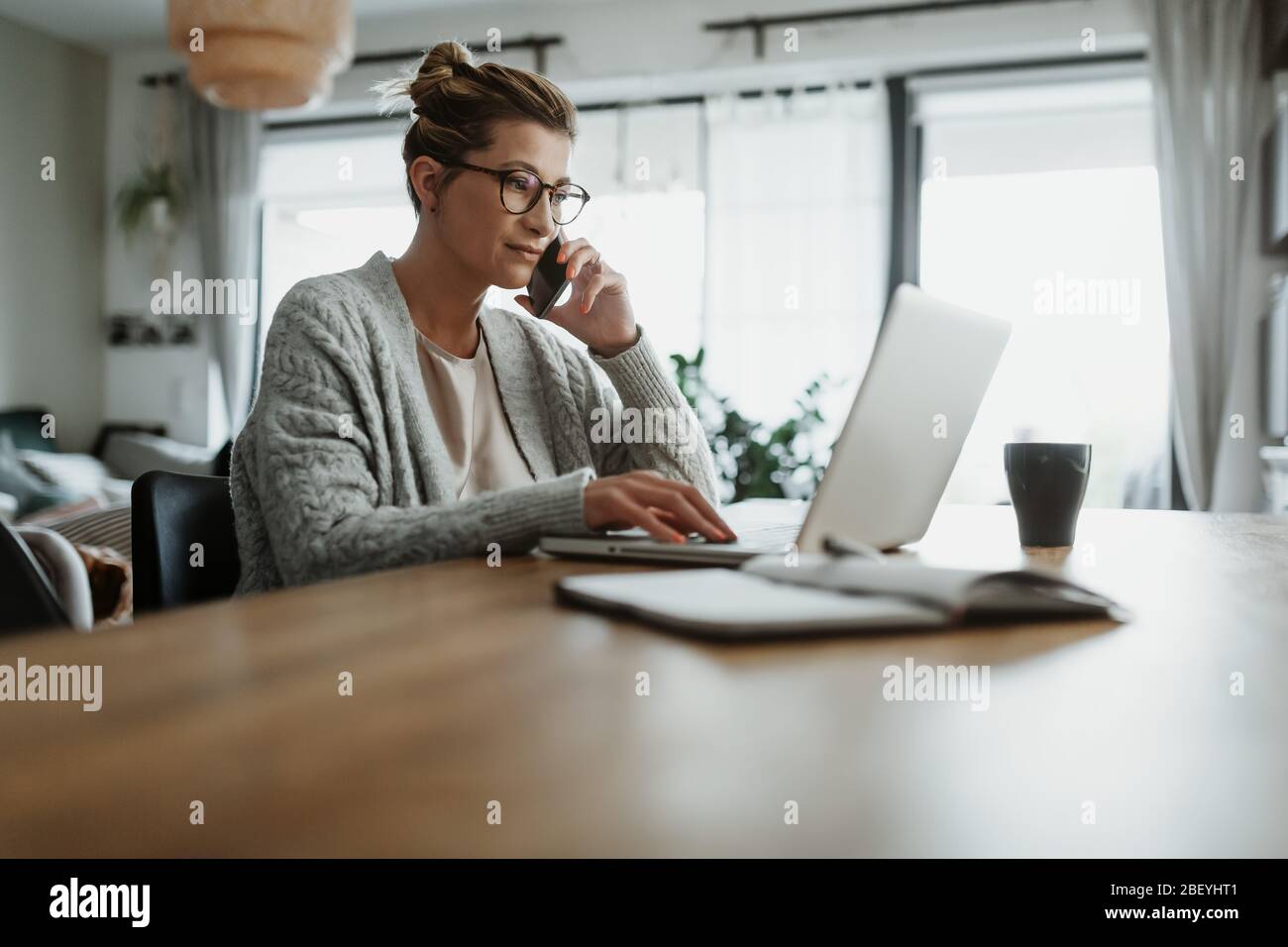 Donna d'affari che lavora su un computer portatile seduto a casa e che gestisce la sua attività tramite ufficio domestico durante la quarantena di Coronavirus o Covid-19 Foto Stock