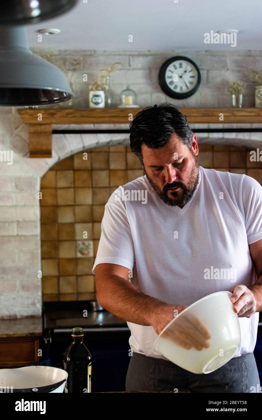 Ritratto Fotografia di un uomo che prepara pane di pasta frolla cotto in casa nella sua cucina casale, dotata di un AGA blu navy Foto Stock