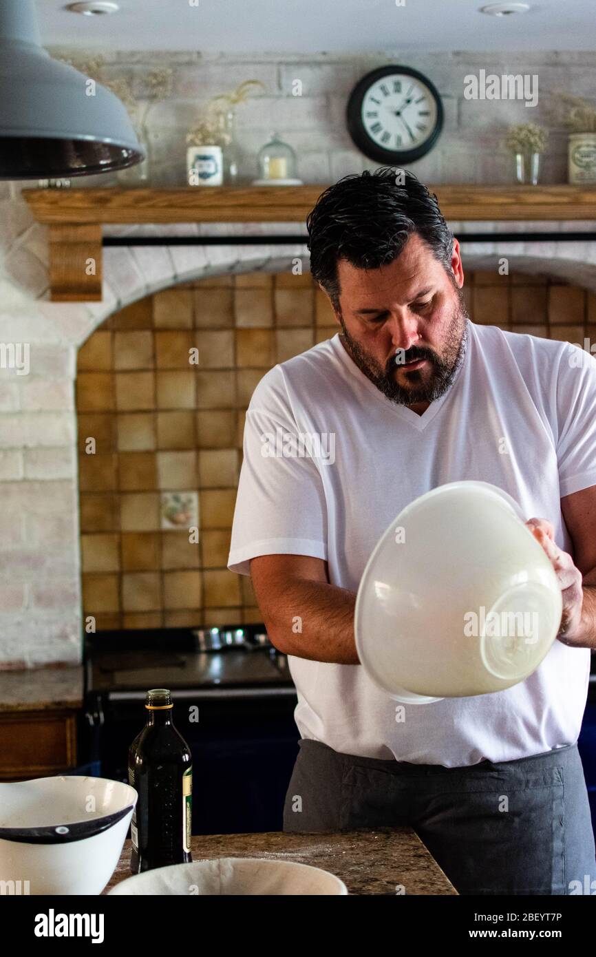 Ritratto Fotografia di un uomo che prepara pane di pasta frolla cotto in casa nella sua cucina casale, dotata di un AGA blu navy Foto Stock
