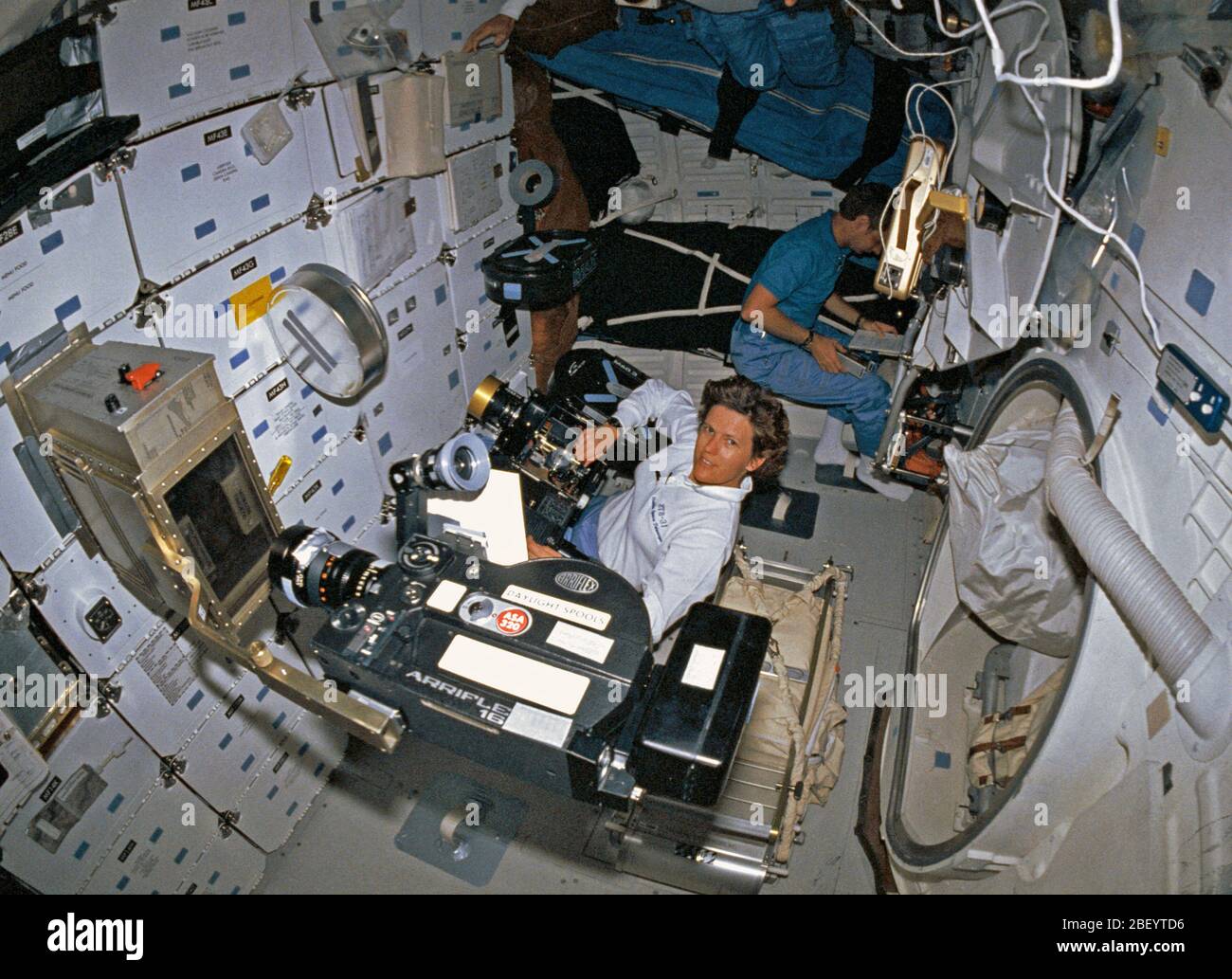 (24-29 aprile 1990) --- una fotocamera da 35mm con un "fish eye" lente catturato questo angolo di alta immagine sulla scoperta di middeck. Astronauta Kathryn D. Sullivan funziona con la fotocamera IMAX in primo piano, mentre astronauta Steven A. Hawley consulta un elenco di controllo in angolo. Un Arriflex motion picture fotocamera registra studente ione esperimento arco in apparecchiature montate su gavone di stivaggio. L'esperimento è stato il progetto di Gregorio S. Peterson, attualmente uno studente presso la Utah State University. Foto Stock