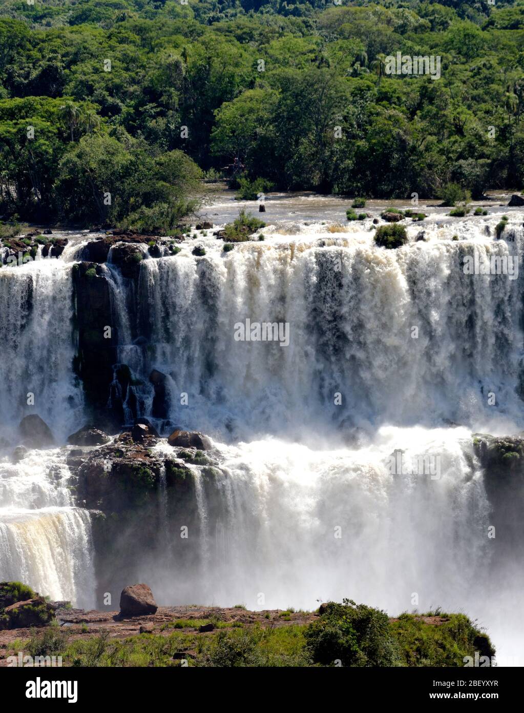 Acqua che si riversa sulle cascate di Iguacu, Brasile, sotto la luce del sole Foto Stock