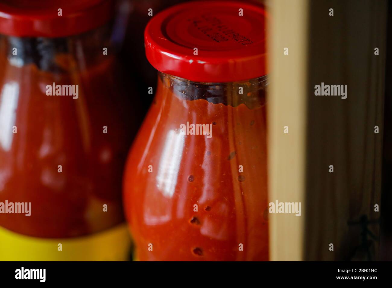 Profondità di campo bassa (fuoco selettivo) dettagli con pasta di pomodoro in una bottiglia di vetro sullo scaffale nella dispensa casa. Foto Stock