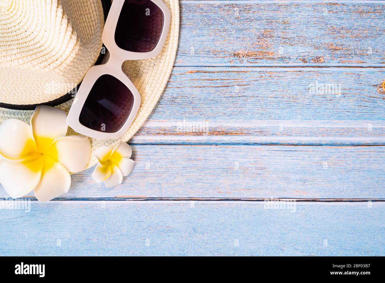 Bella vacanza estiva, accessori da spiaggia, occhiali da sole, cappello e fiore su sfondi in legno Foto Stock