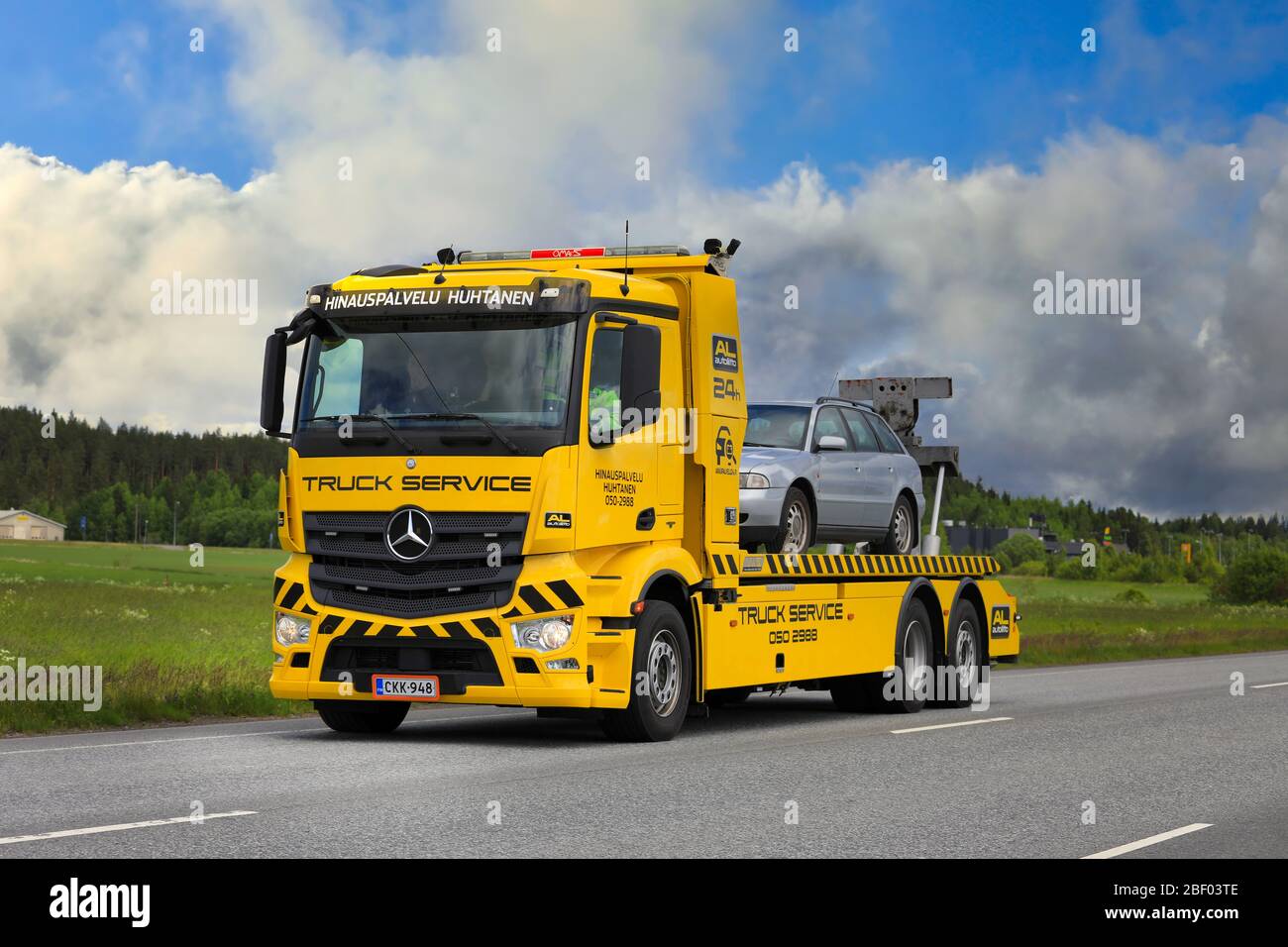 Il rimorchio giallo Mercedes-Benz di Hinauspalvelu Huhtanen trasporta l'automobile di guasto sull'autostrada in un giorno dell'estate. Forssa, Finlandia. 23 giugno 2017. Foto Stock