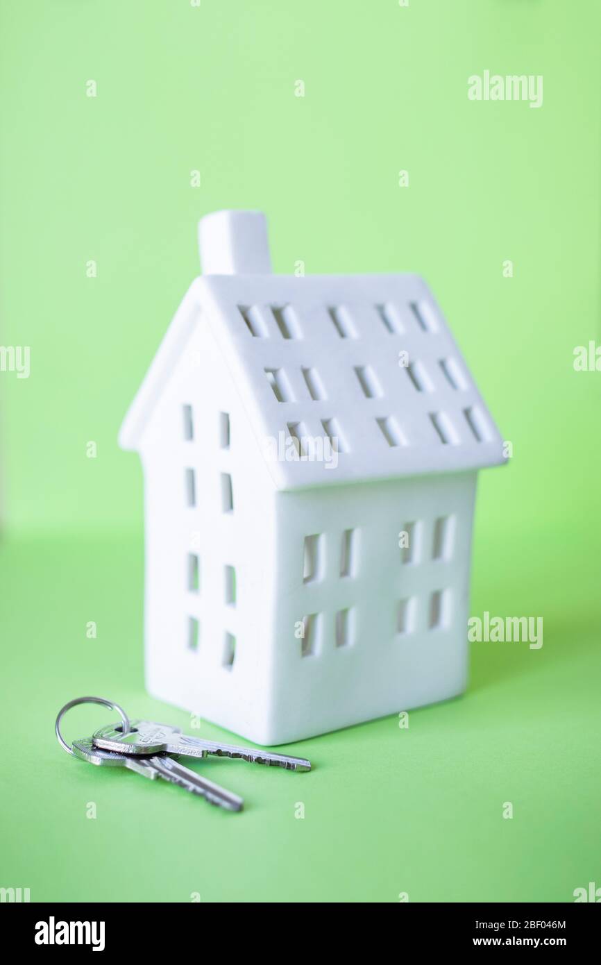 Una casa in miniatura con chiave isolata su sfondo verde Foto Stock