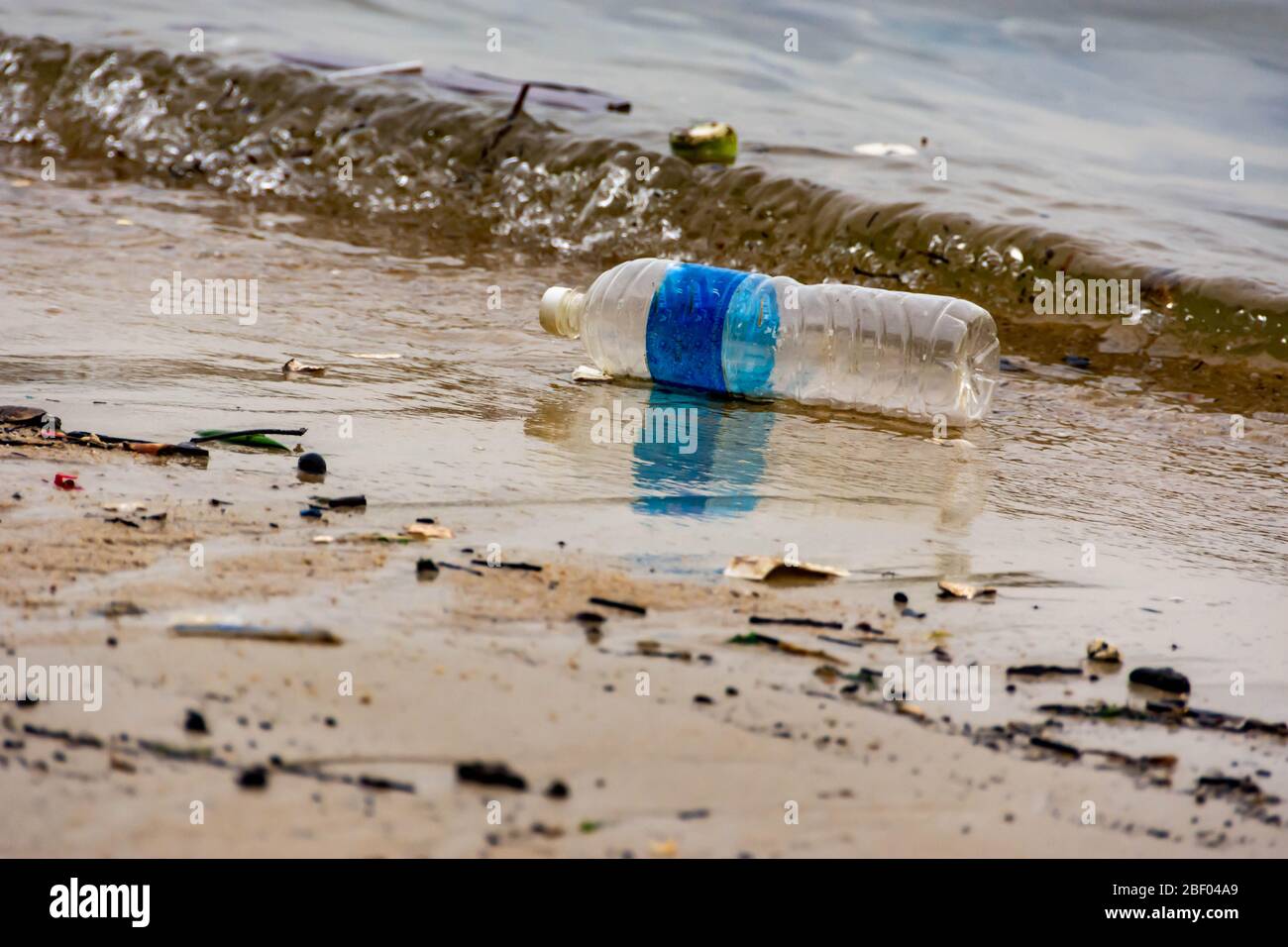 Rifiuti di plastica della bottiglia d'acqua su una baia che inquina l'oceano. Rifiuti di plastica gettati dalla spiaggia Foto Stock